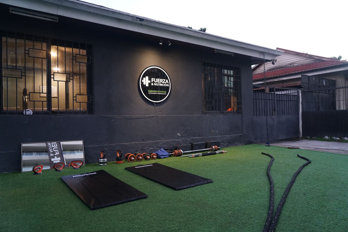 Fachada del gimnasio con el logo y el patio de pasto sintético